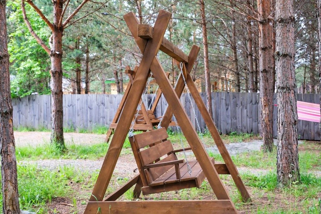 Деревянные качели в соснах